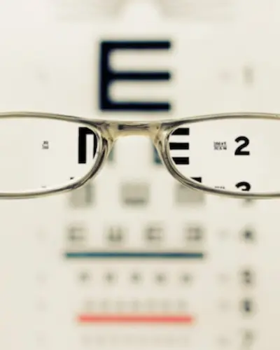 Clarity Article - blurry vision test in background, glasses in foreground making the the blurry clear. Maximize clarity.